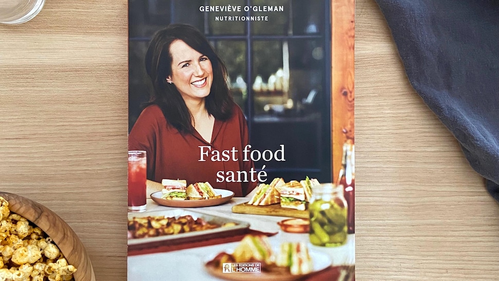 Le nouveau livre Fast food santé de Geneviève O'Gleman est posé sur une table à côté d'un bpl de pop corn et d'un verre d'eau.