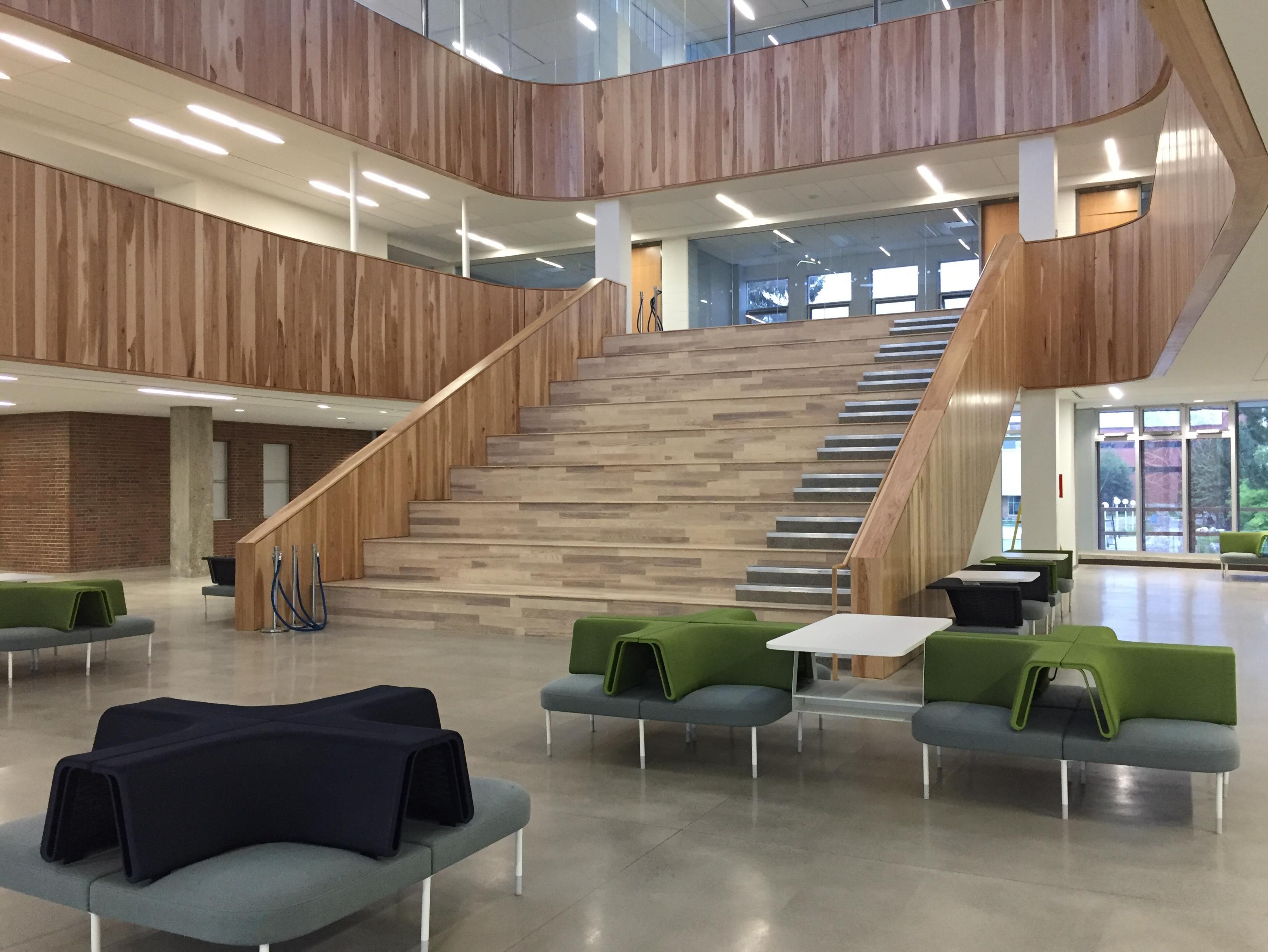 Le nouvel atrium de l'Université Laurentienne est tout en bois, avec quelques fauteuils pour accueillir les élèves. Il compte de grands escaliers.