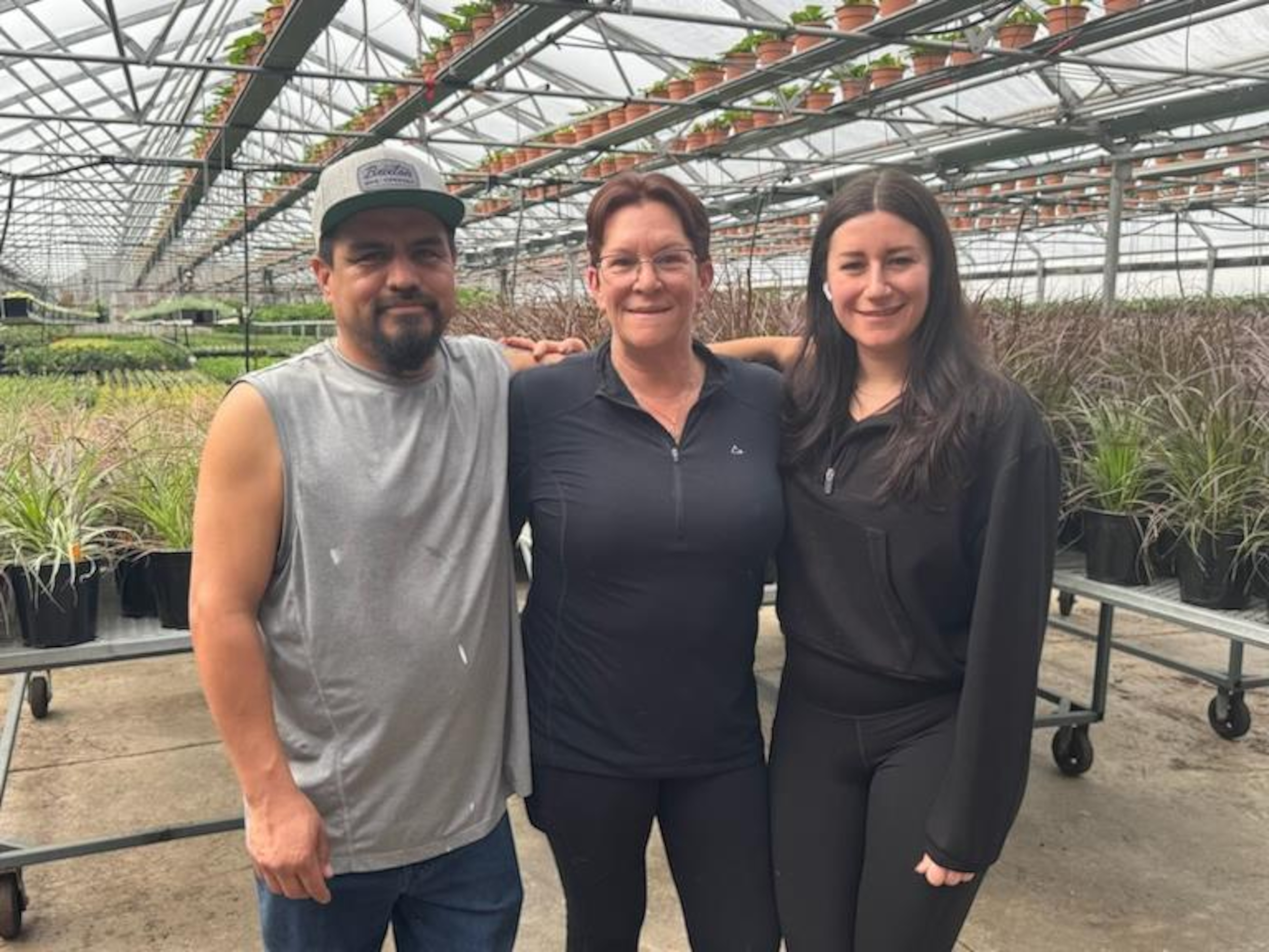 Les trois personnes s'enlacent au sein des plantes de la serre.