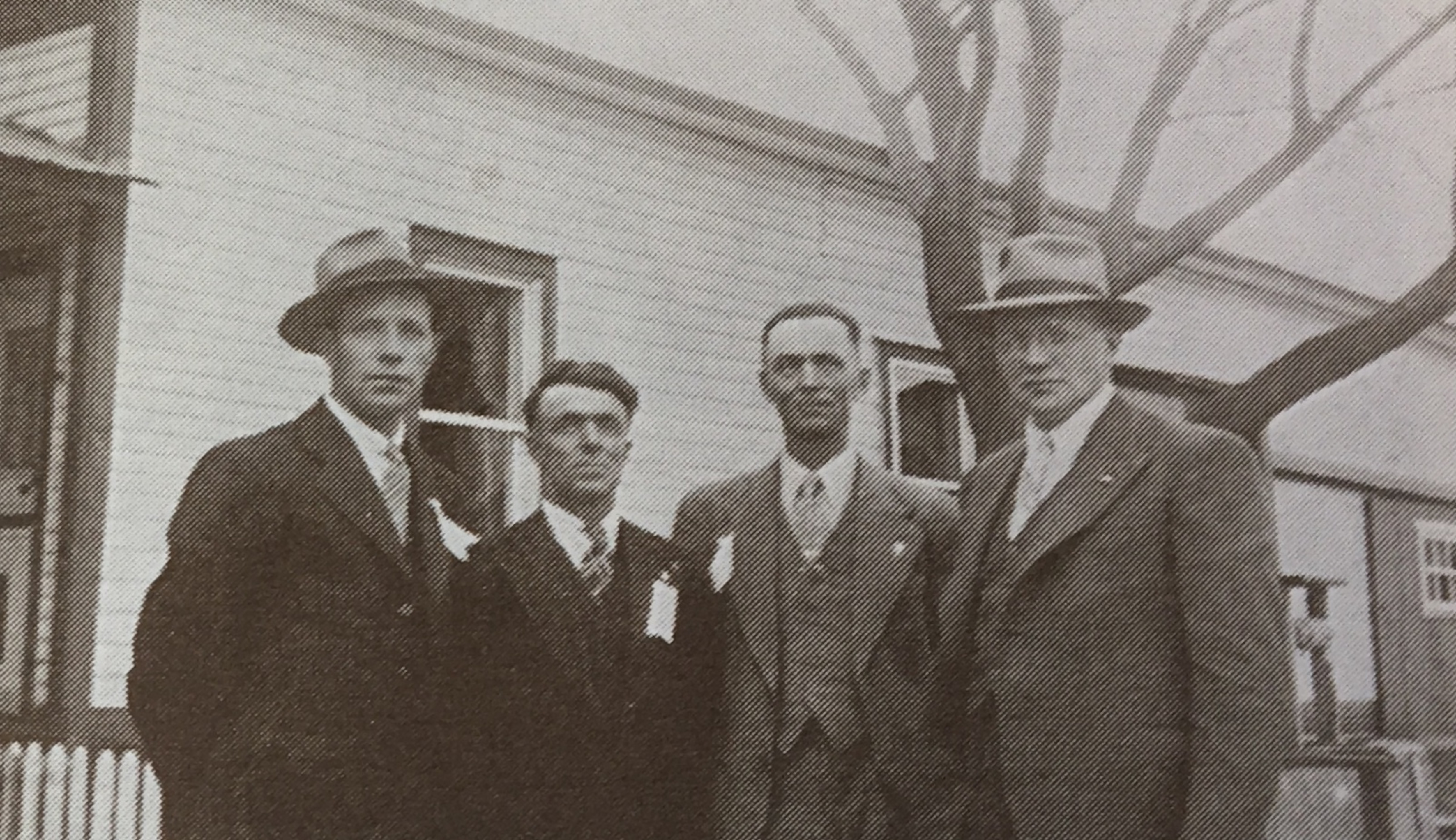 Sur cette photo d'archive, quatre hommes posent devant une maison.