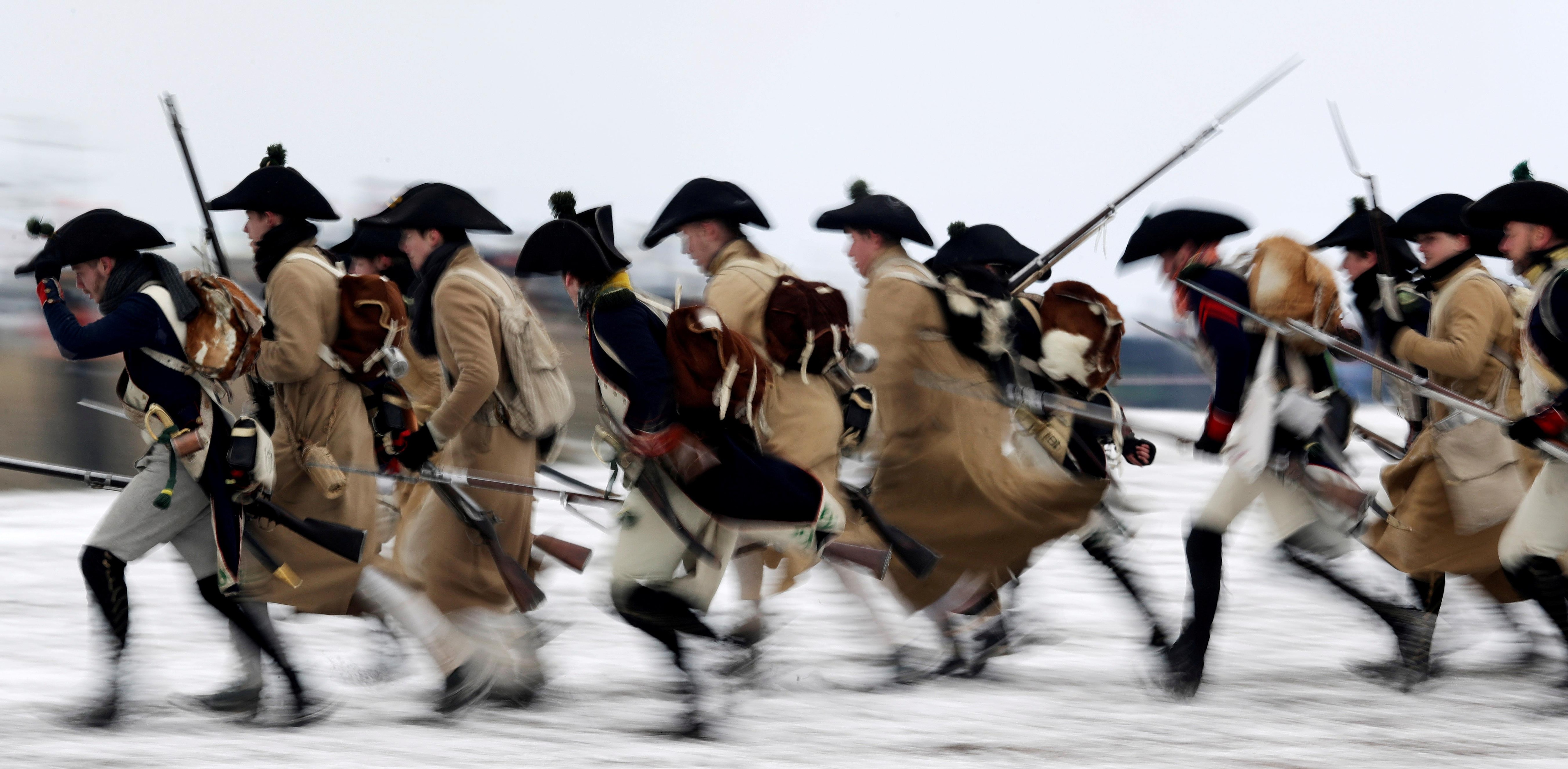 Photo d'hiver qui montre des hommes habillés en soldats d'époque courant dans la neige.