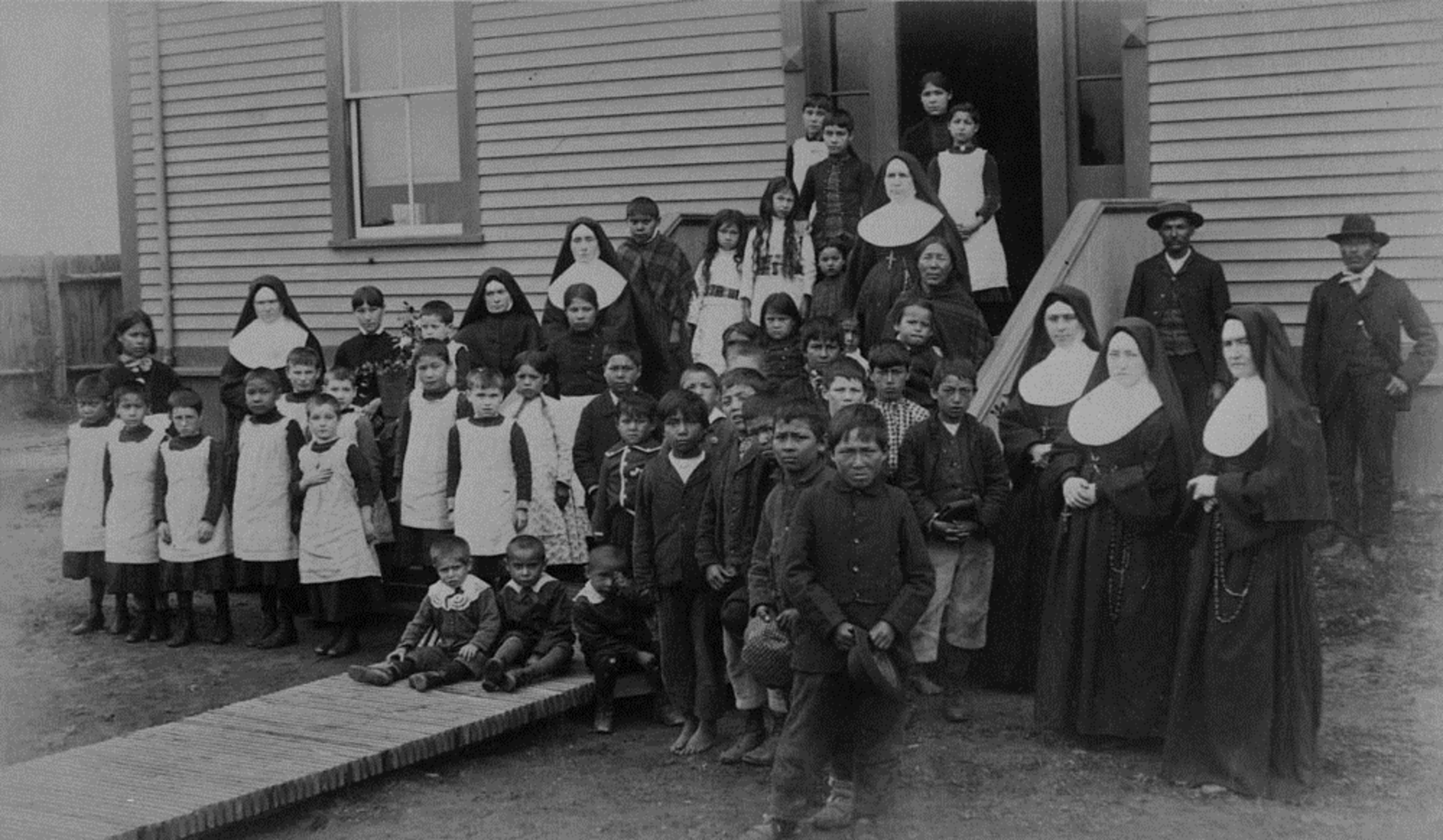 Groupe d'élèves, religieuses et hommes autochtones posant devant l'école, foyer fédéral de Port Harrison (Inukjuak),   Québec, vers 1890