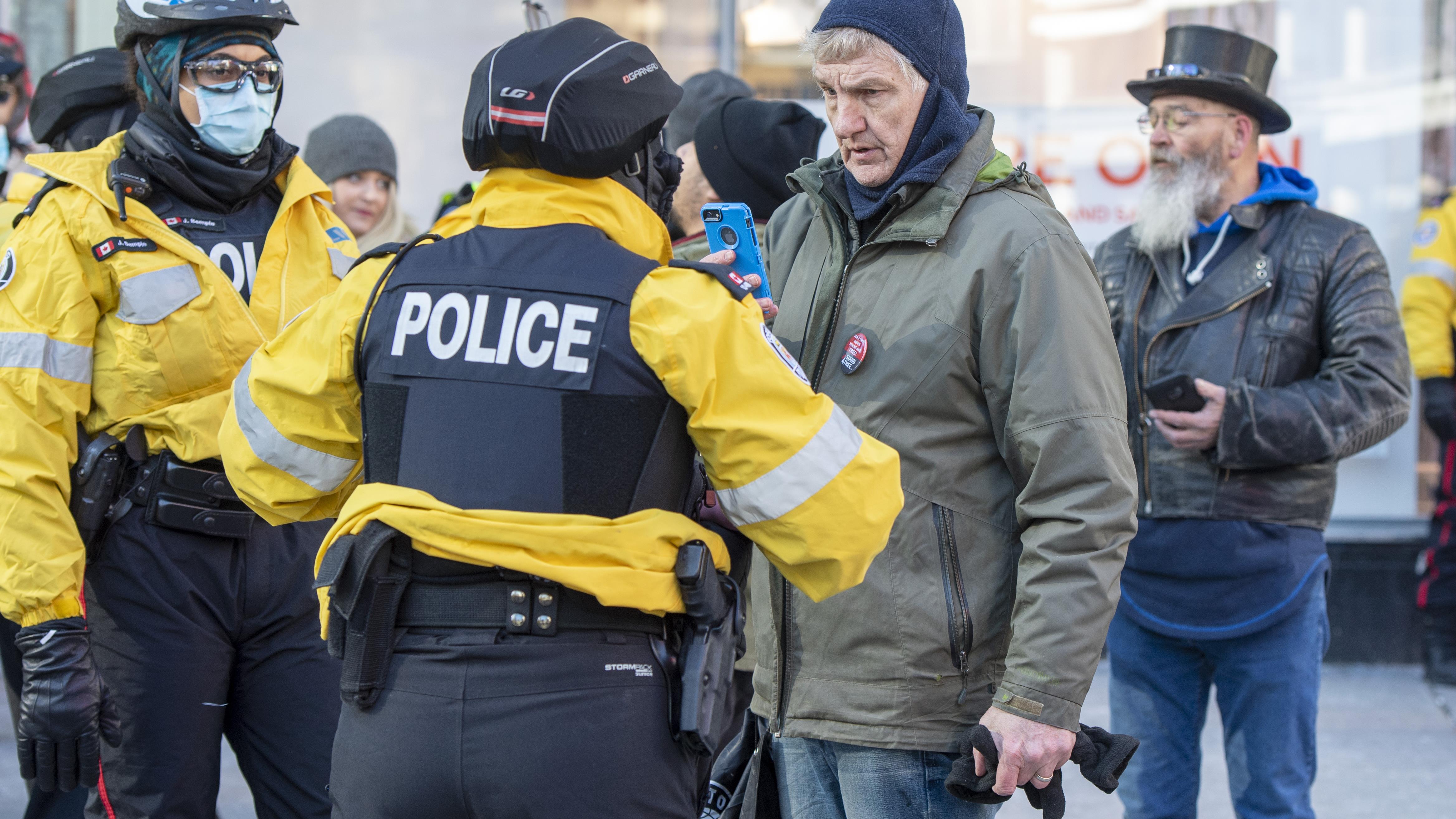 Policías en Toronto conversan con una manifestante anti-mascarilla.