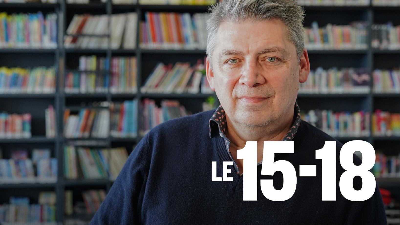 Michel Jean devant des rayons de livres.