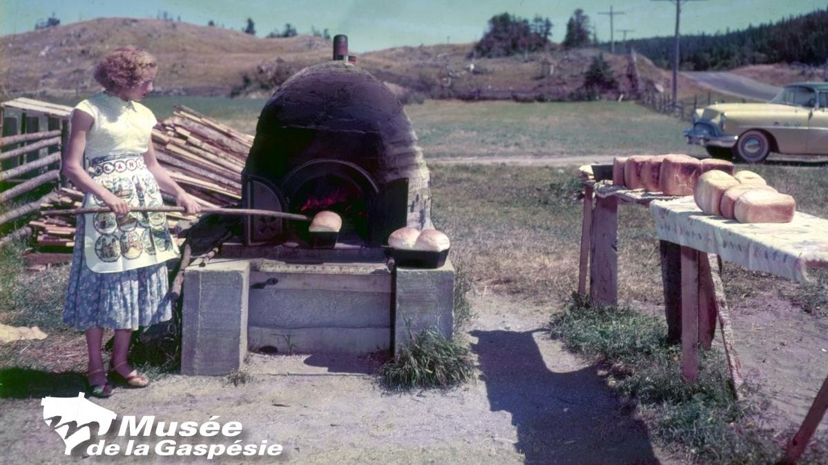 Négatif représentant une jeune femme sortant un pain d’un four à pain vers 1950.