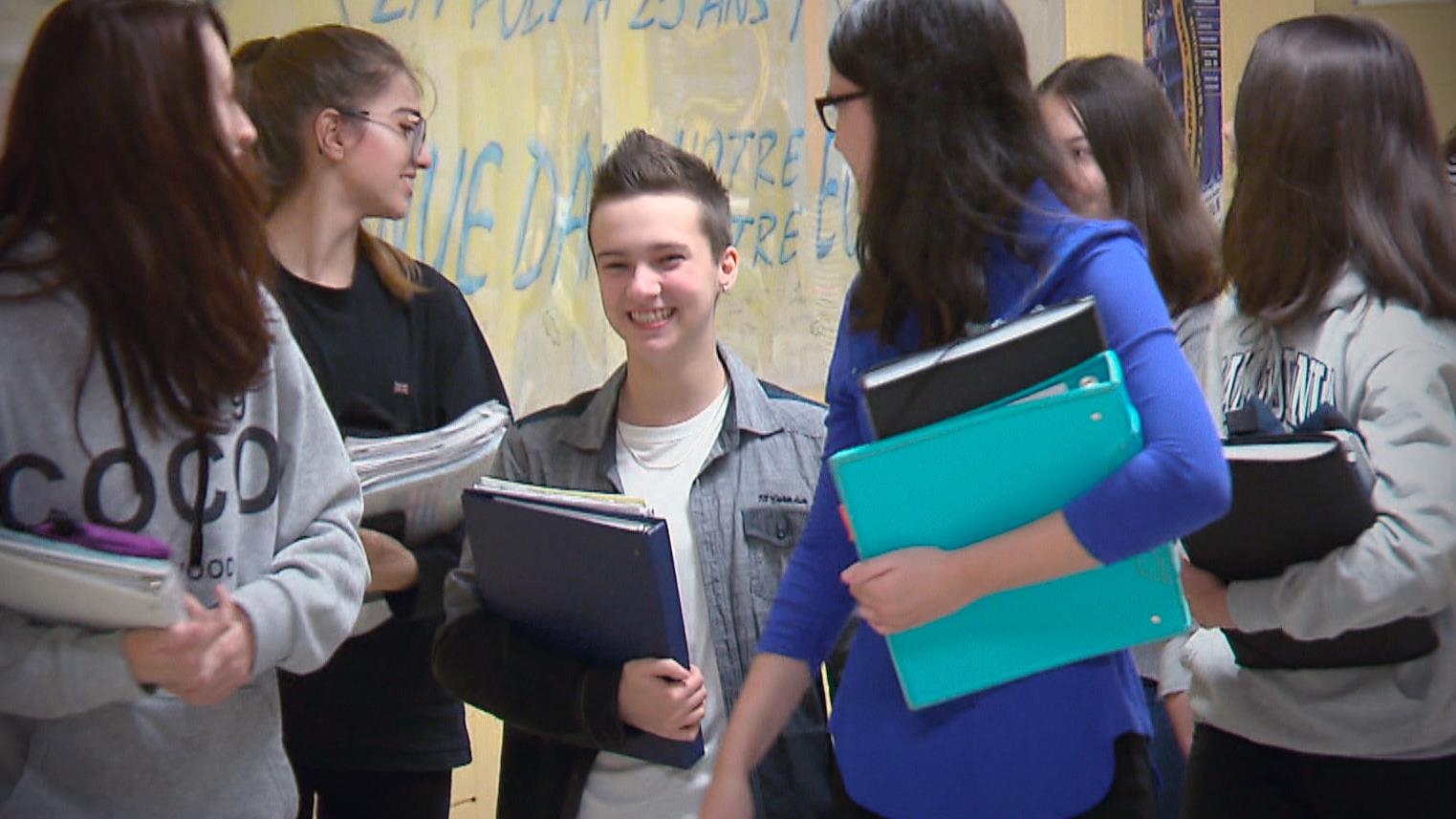 Loukas dans un corridor de l'école, entouré de ses amies