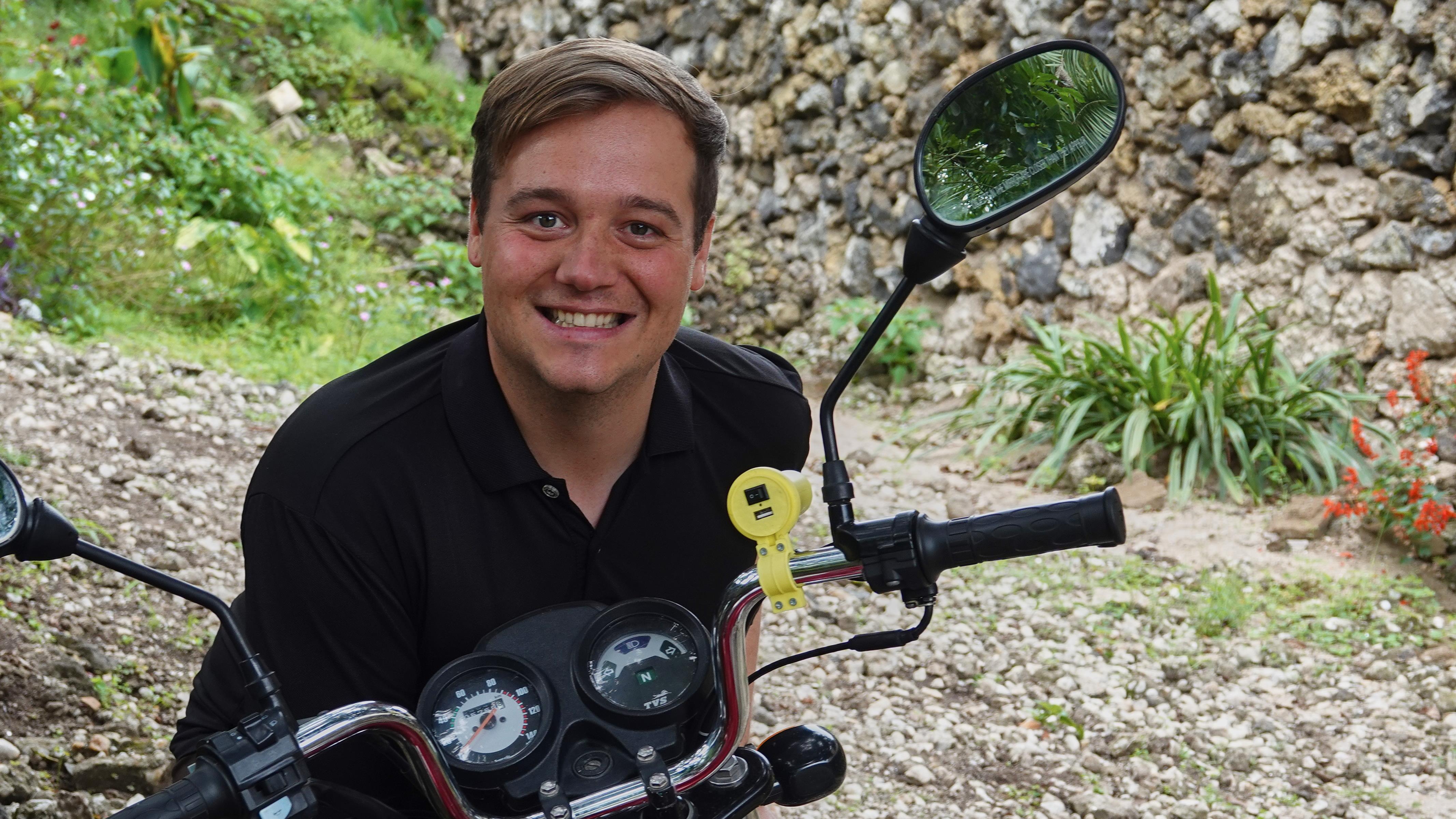 Nathanaël Hollands posant avec un modèle de son chargeur USB sur une moto