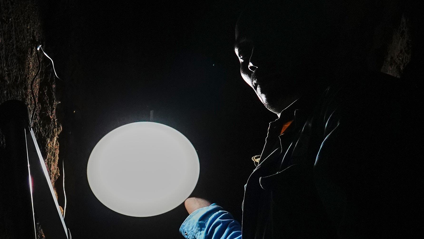Un technicien est en train d’installer des luminaires à l'intérieur d'une maison rwandaise