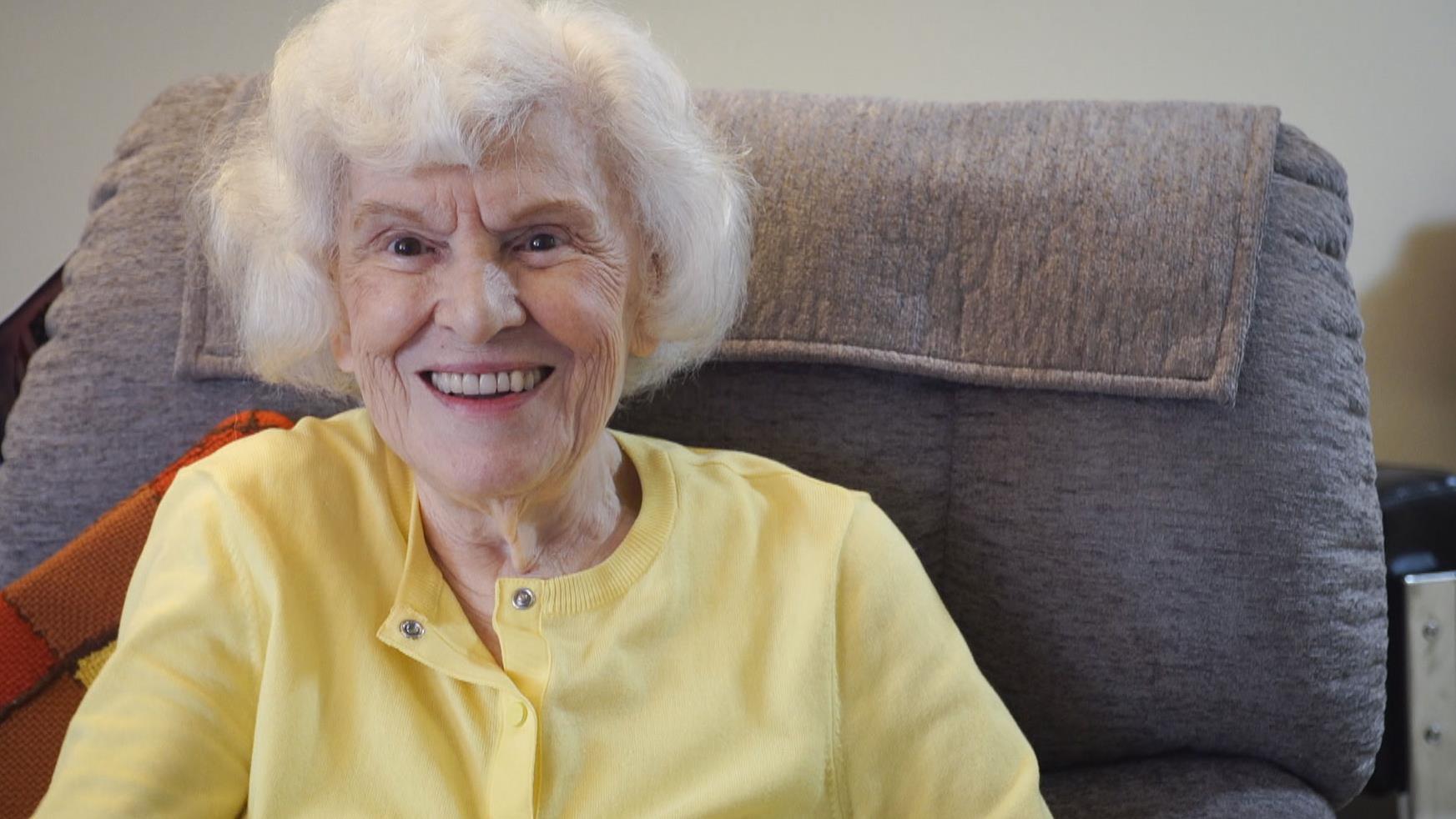 Annette sourit sur un fauteuil.