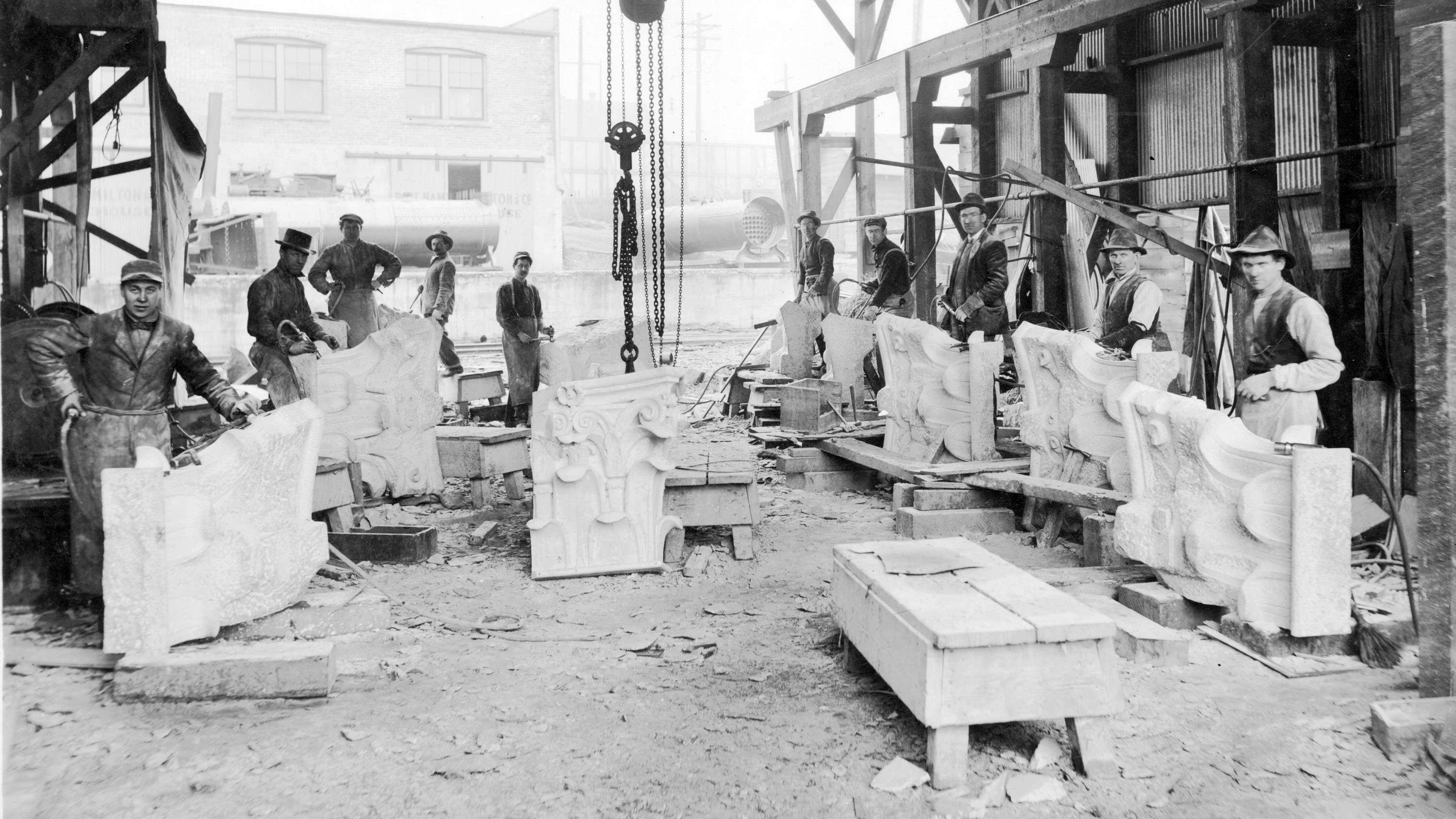 Des travailleurs tiennent des moulures qui serviront à la construction du bâtiment du crédit foncier franco-canadien.