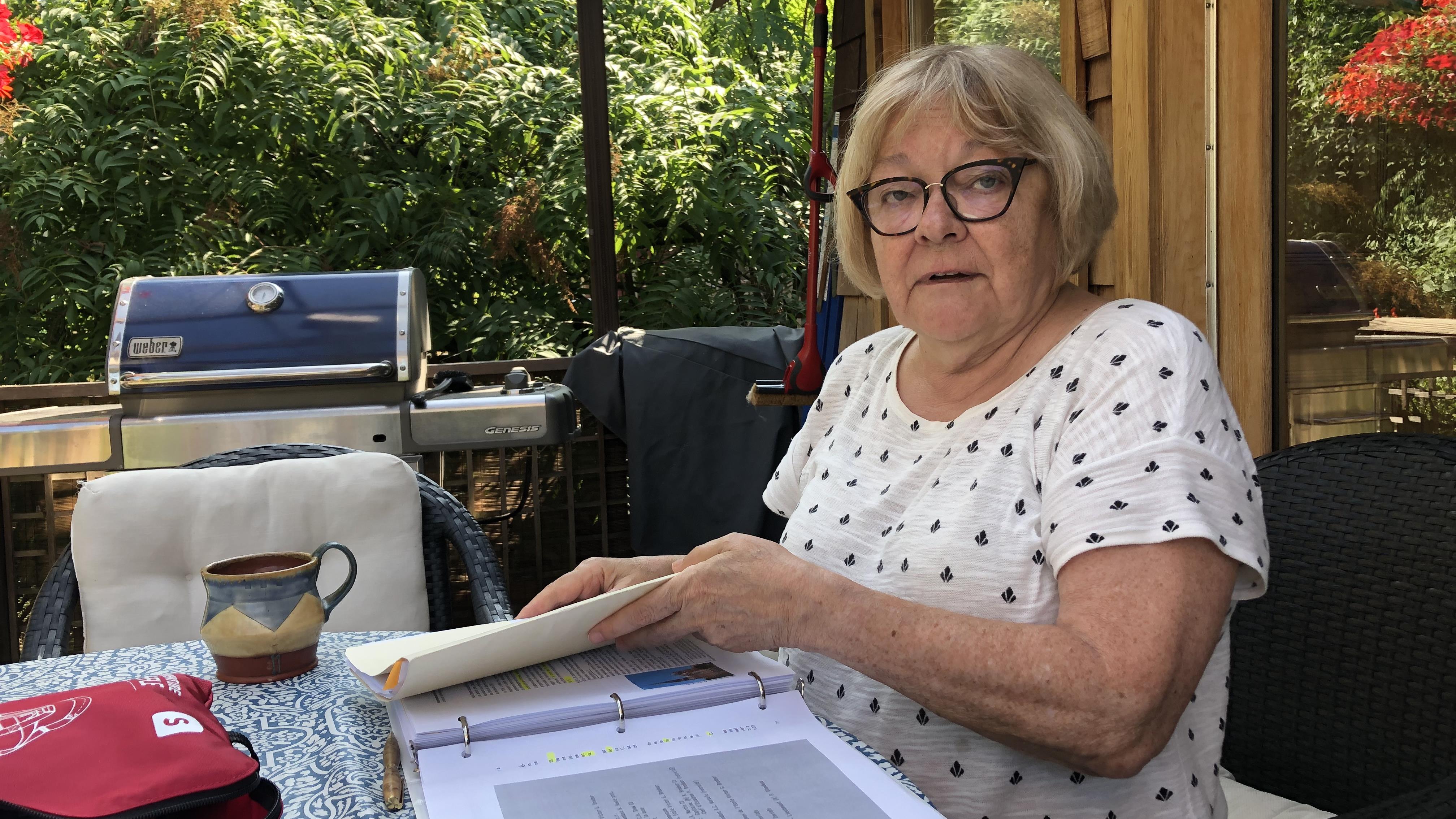 Yseult Friolet, ancienne enseignante, devant des documents sur une table à l'extérieur.