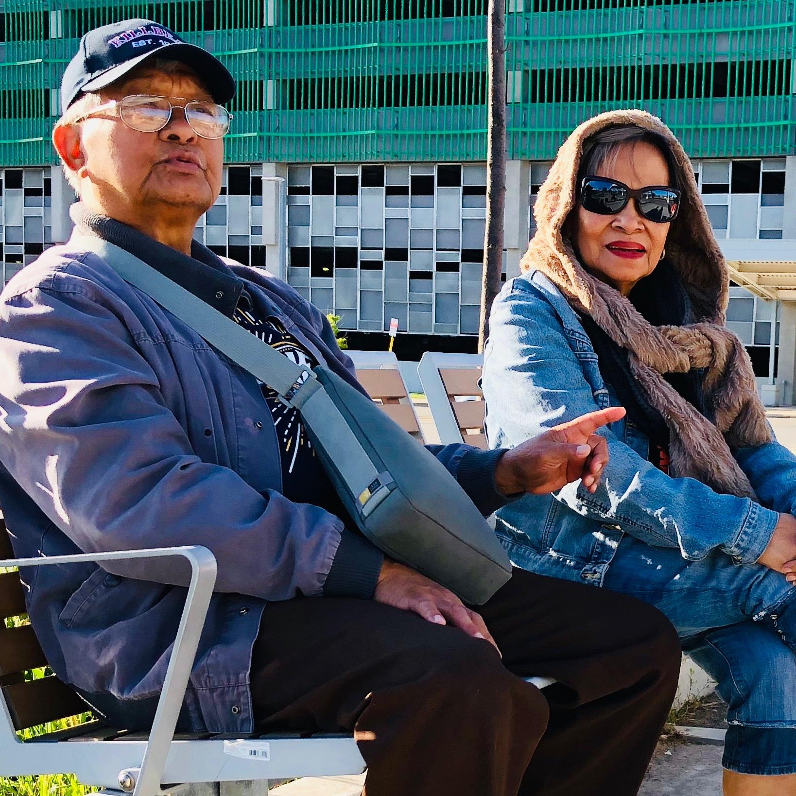 La pareja está sentada en un banco de la estación de tren.