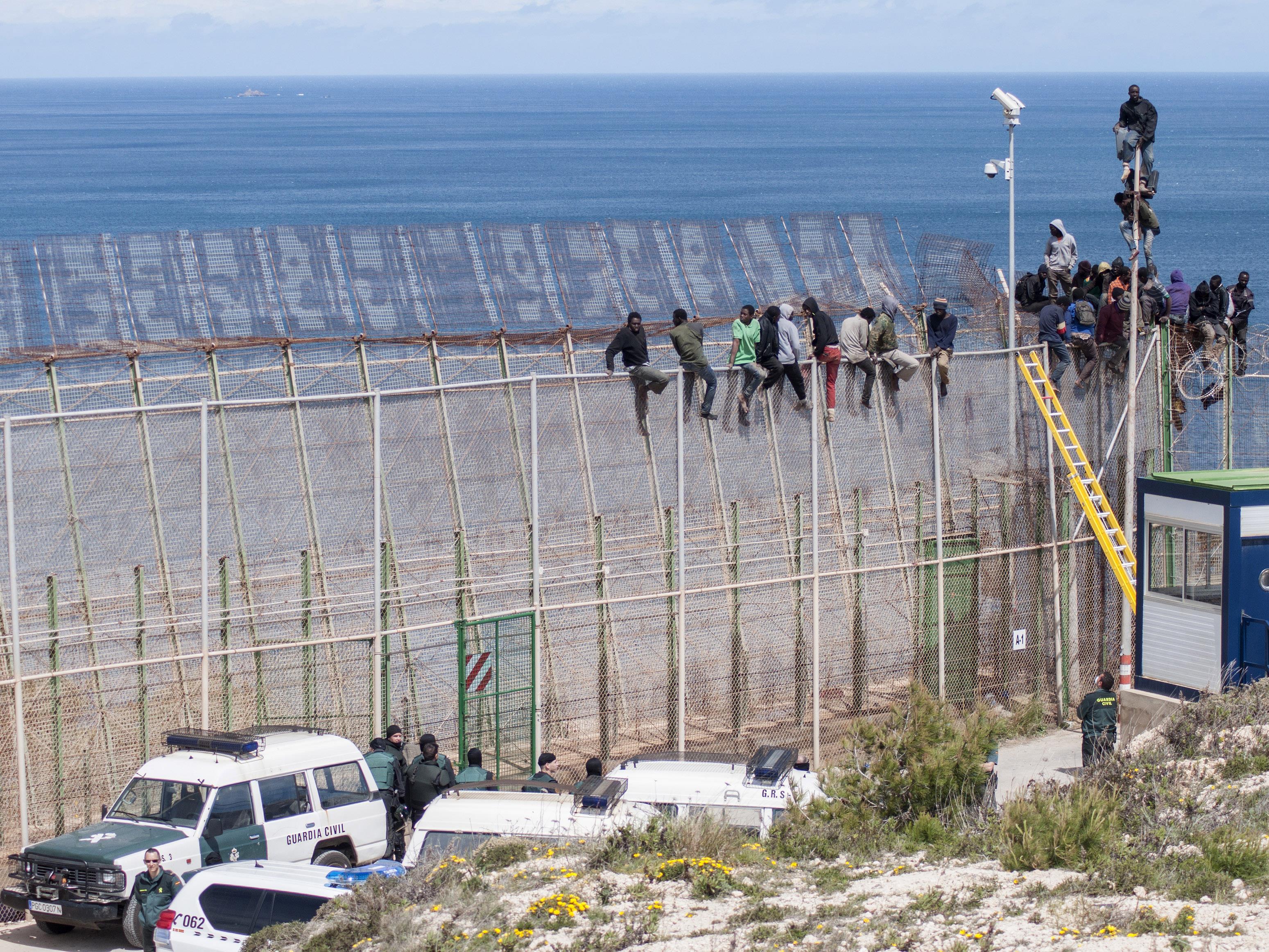 Des migrants africains tentent de franchir la frontière clôturée entre le Maroc et l'Espagne, dans l'enclave espagnole de Melilla en avril 2014.