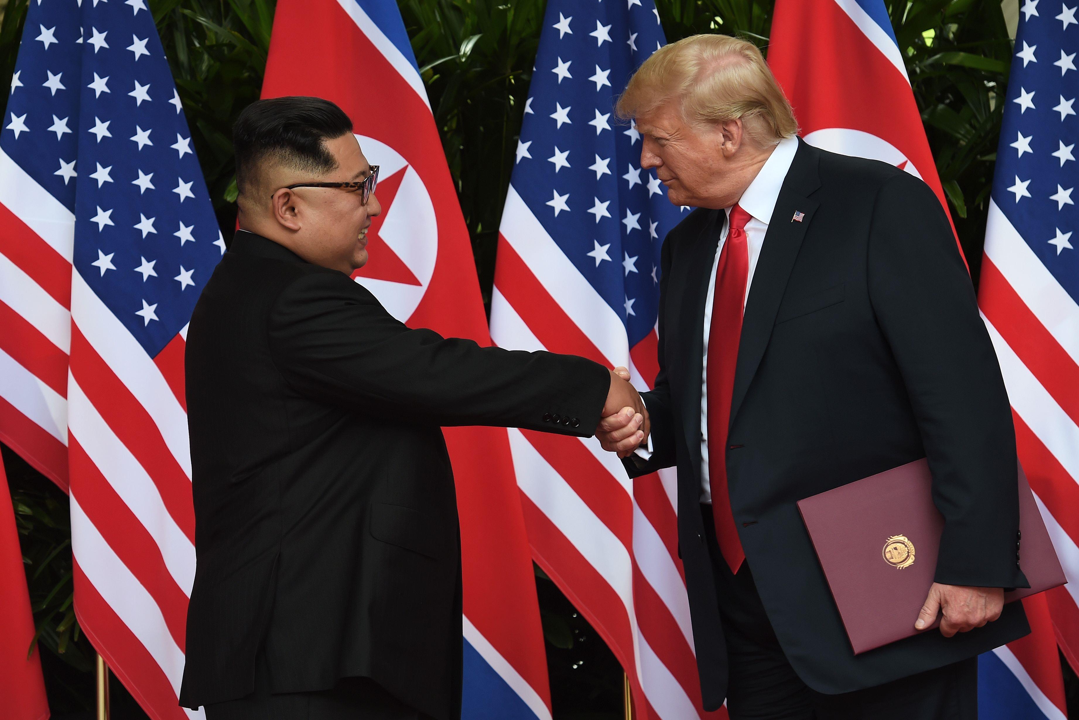 Kim Jong-un serre la main à Donald Trump après avoir pris part à une cérémonie de signature à la fin de leur sommet, à l'hôtel Capella sur l'île de Sentosa, à Singapour, le 12 juin 2018.