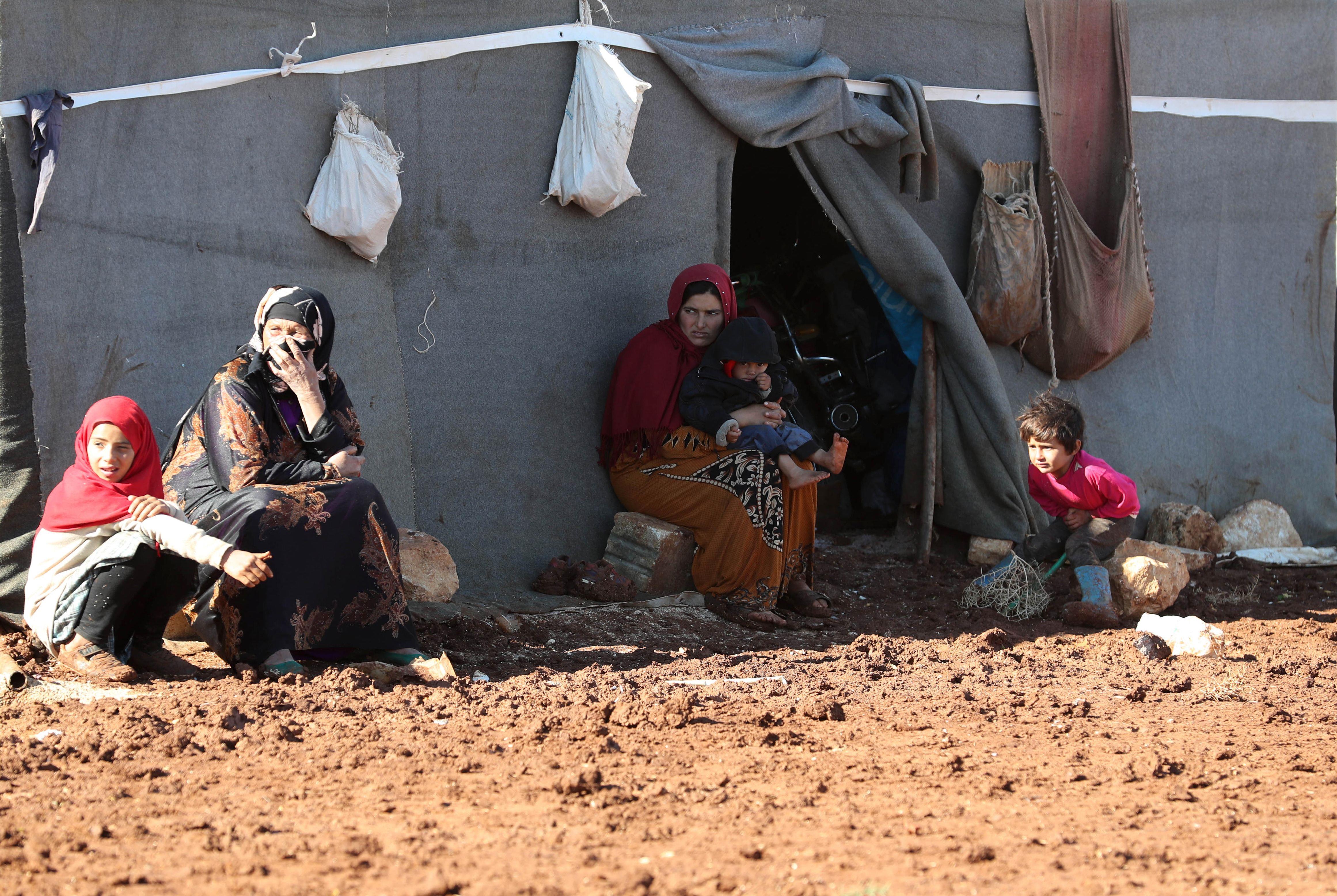 Des femmes et des enfants syriens déplacés sont assis devant leur tente dans le camp de Kafr Dariyan, à proximité de la frontière avec la Turquie, le 26 octobre 2018.