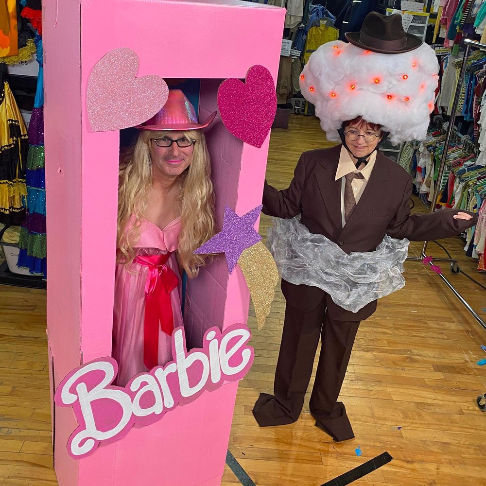 Jean-René Dufort déguisé en poupée Barbie dans une boîte et Chantal Lamarre habillée en complet cravate jumelé à une bombe atomique.