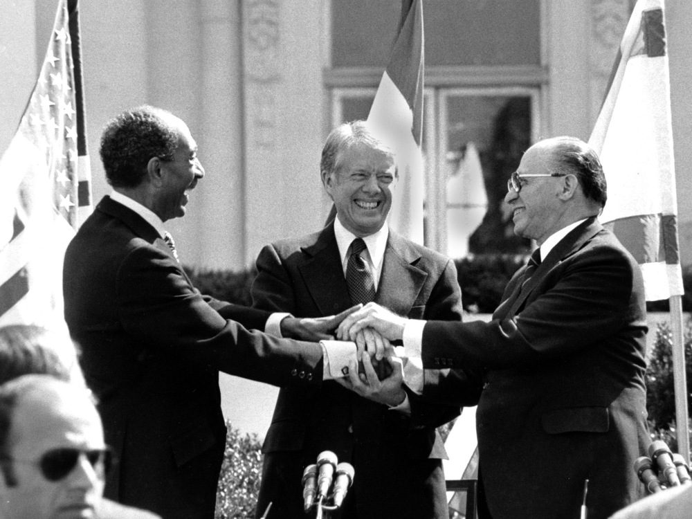 Les trois hommes se serrent les mains.