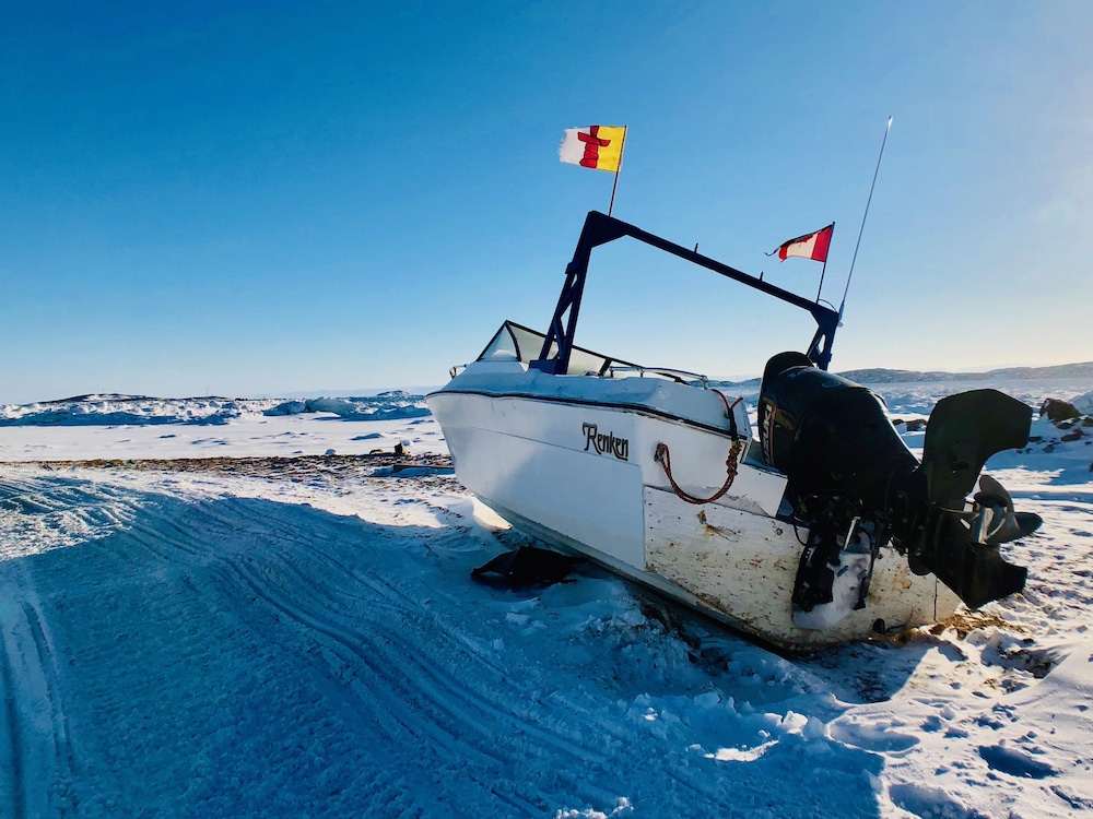 Les drapeaux du Nunavut et du Canada flottent sur un bateau qui attend l’arrivée de l’été dans la baie de Frobisher.
