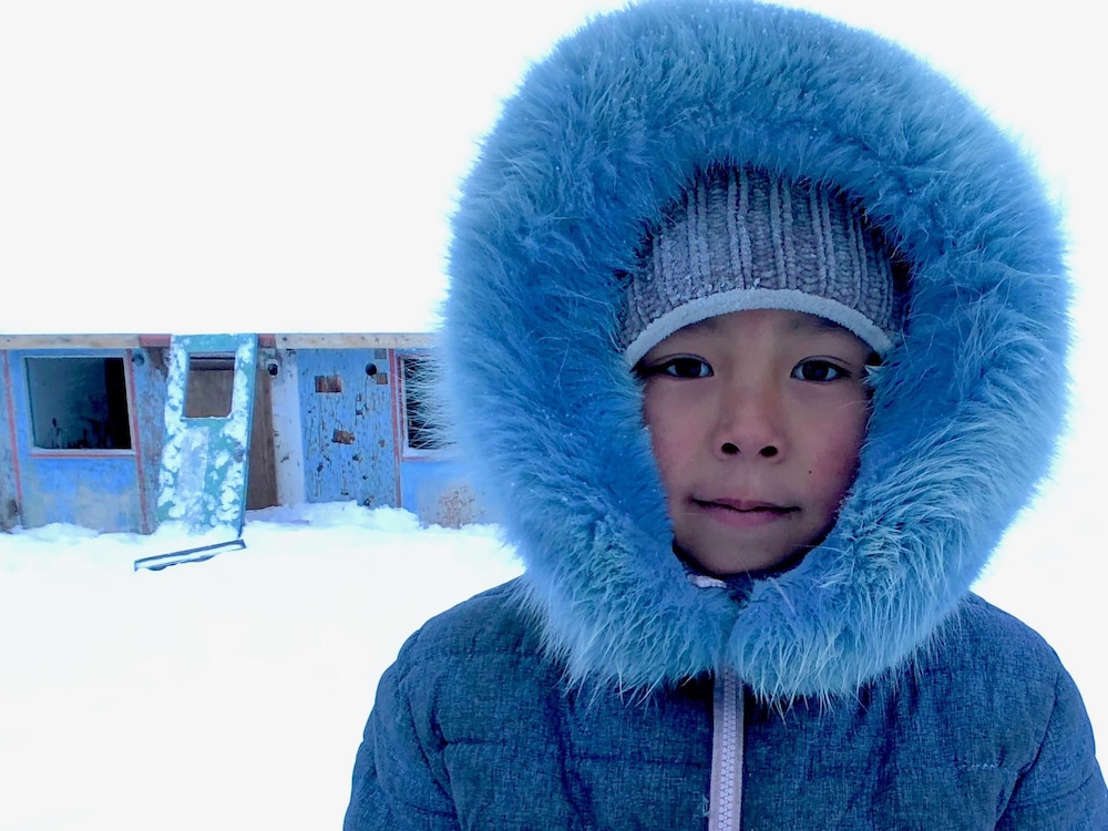 Une jeune Inuite devant une maison abandonnée dans la communauté insulaire de Qikiqtarjuaq. Le logement représente un énorme défi de santé publique au Nunavut.