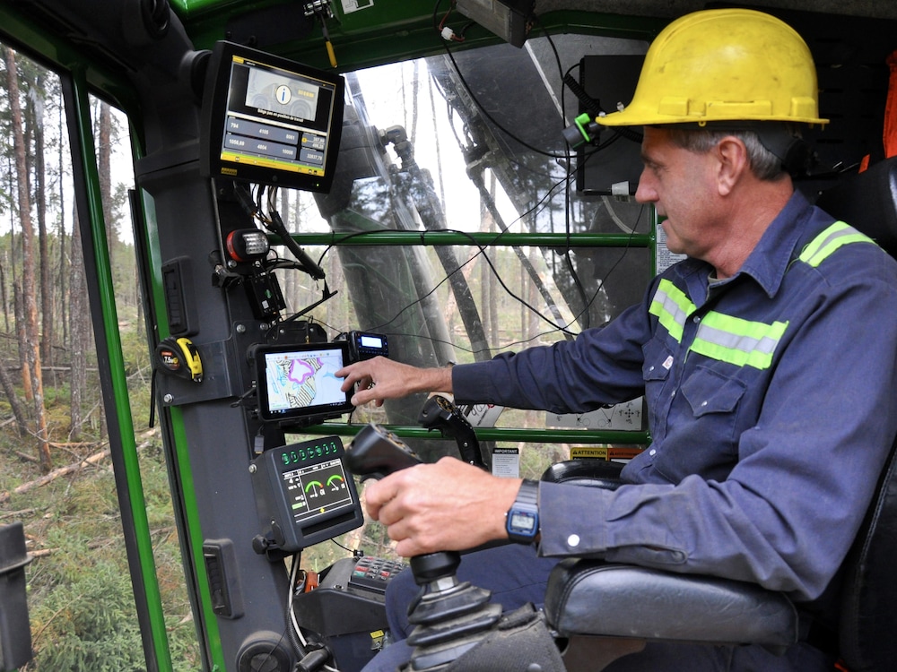 Intérieur de la cabine d’une abatteuse multifonctionnelle dans laquelle l’opérateur pointe le système GPS.
