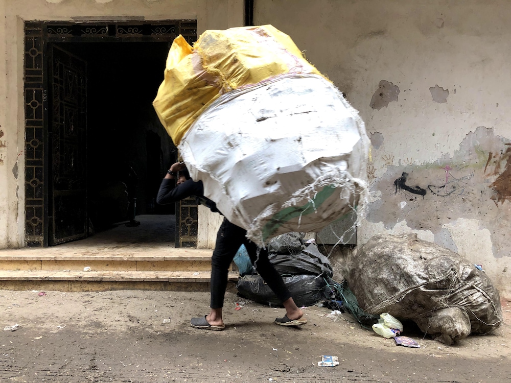 Un homme transporte un ballot d'une matière recyclable.