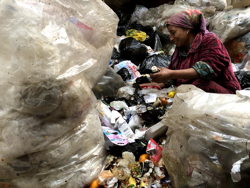 Une femme trie les déchets sans gants.