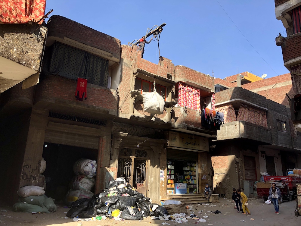 Un homme utilise un palan à corde pour stocker des matériaux recyclables sur le toit de son immeuble.