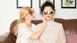 Evelyne Brochu et Virginie Fortin sont assises sur un divan et portent des lunettes colorées ayant des motifs de fruits.