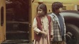 Une jeune fille et un jeune garçon devant un autobus scolaire.