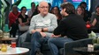 Les deux hommes sont assis sur un fauteuil et discutent.
