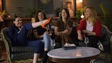 4 femmes rigolent sur un canapé vintage. L'une d'entre elles à une jambe dans les airs.
