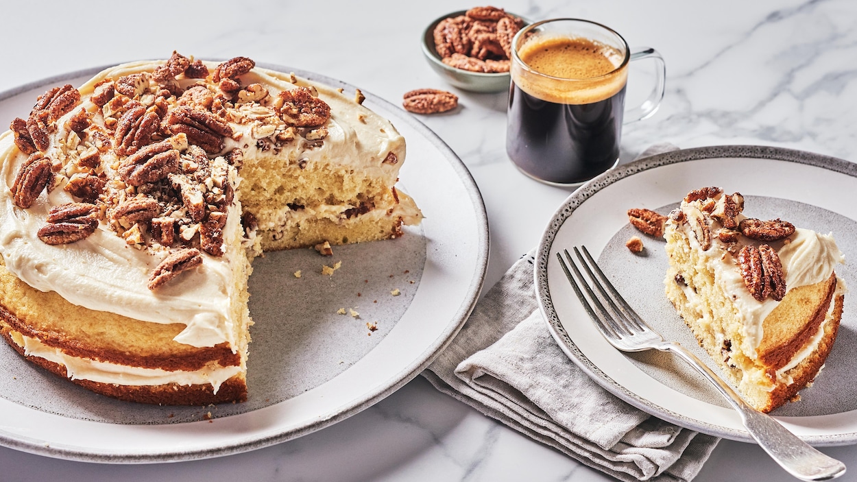 Un gâteau aux pacanes dans une assiette avec une part déjà coupée dans une assiette.
