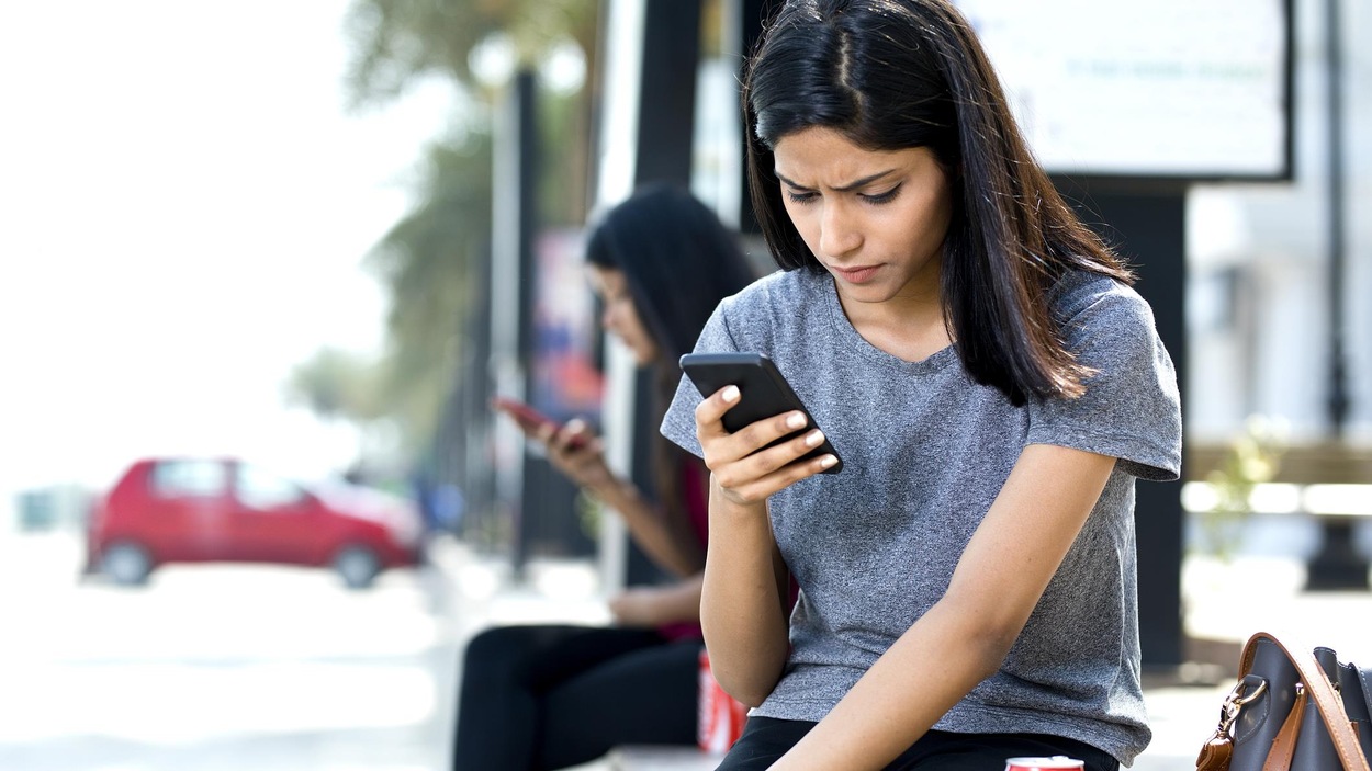 Une jeune femme consulte son téléphone portable. Une jeune femme consulte son téléphone portable.