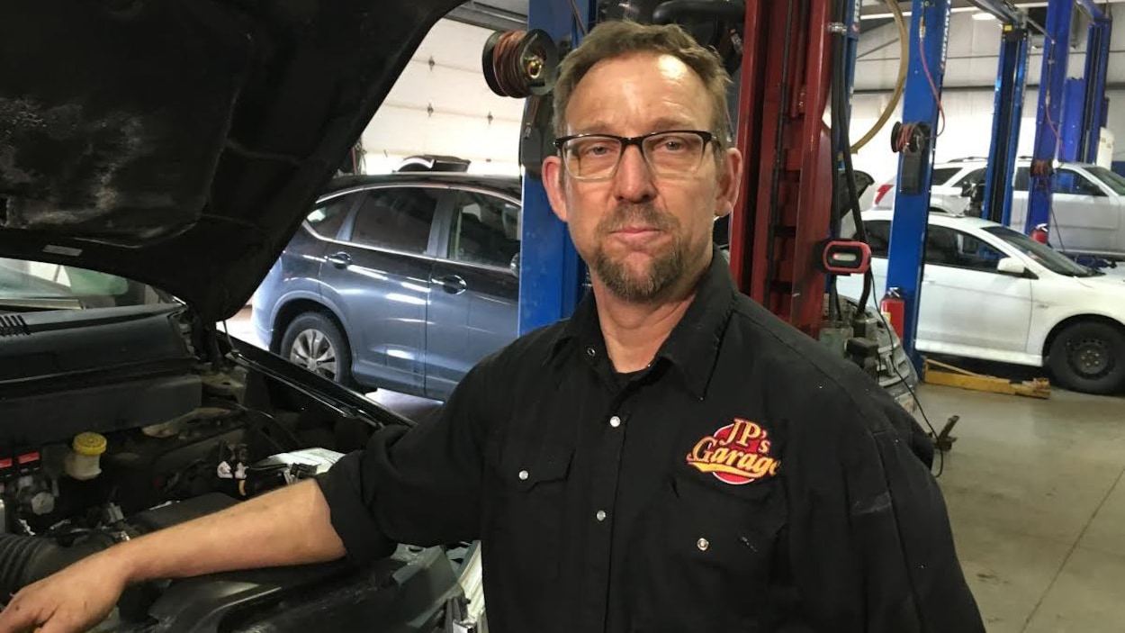 Jean-Paul Belliveau inspecte le moteur d'une voiture Jean-Paul Belliveau inspecte le moteur d'une voiture