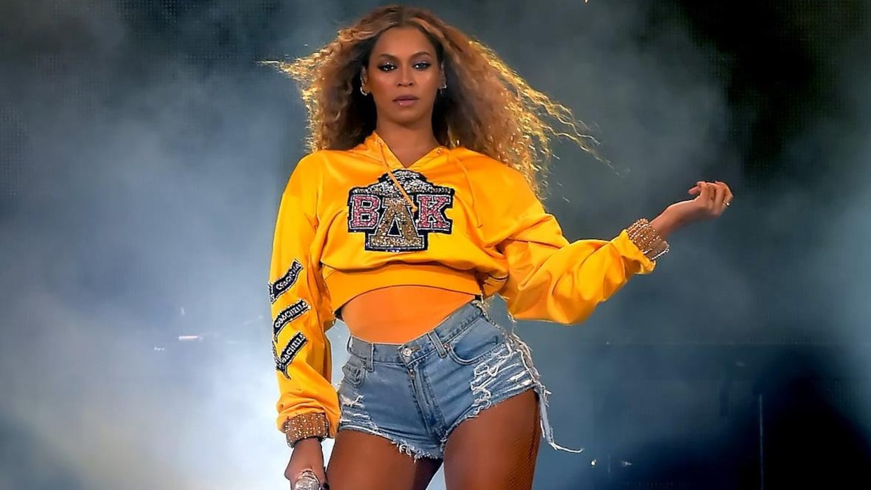 Beyonce porte un chandail jaune et un court short en jean. Beyonce porte un chandail jaune et un court short en jean.