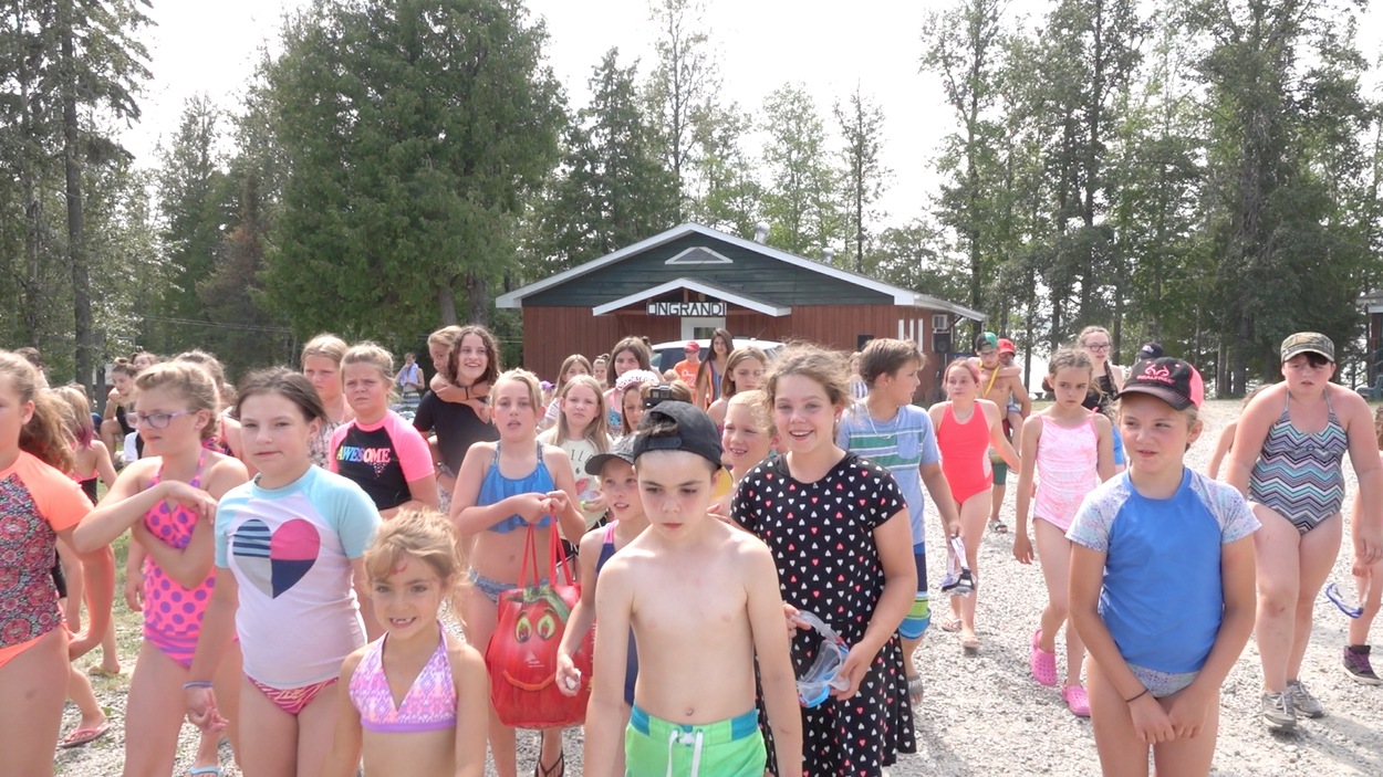 Des jeunes marchent en maillot de bain devant le camp. Des jeunes marchent en maillot de bain devant le camp.