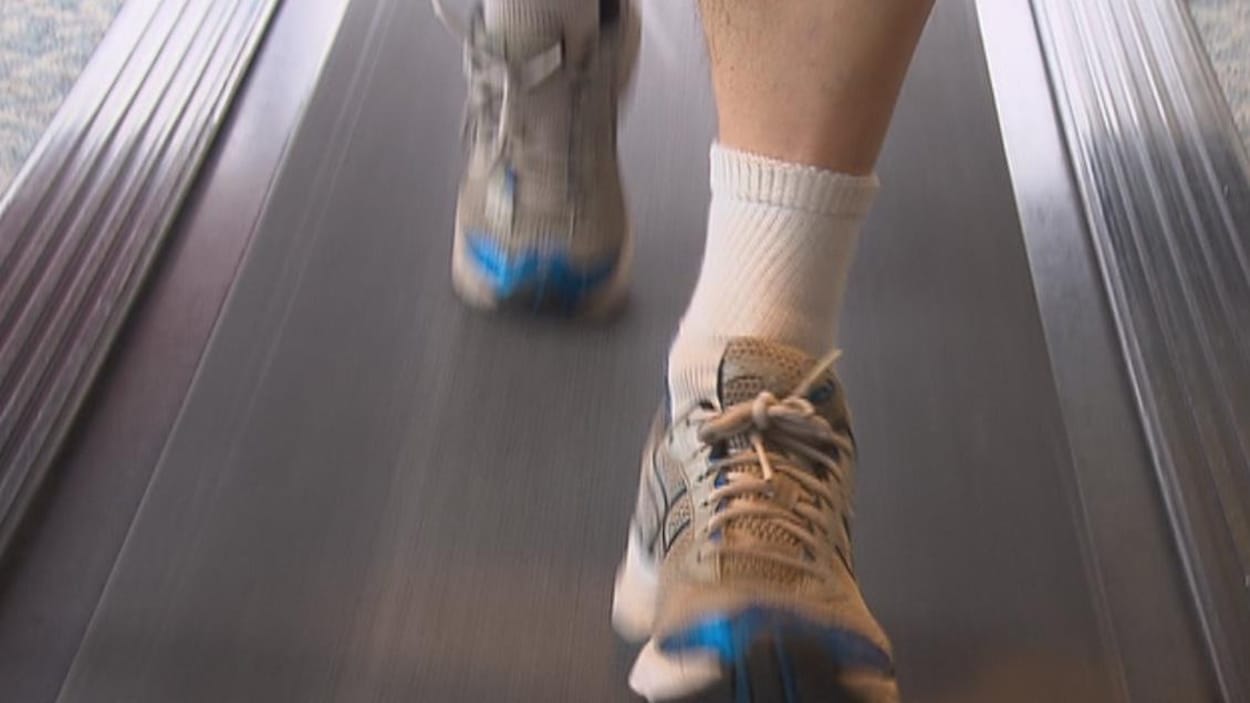 Les pieds d'un homme qui court sur un tapis de course Les pieds d'un homme qui court sur un tapis de course