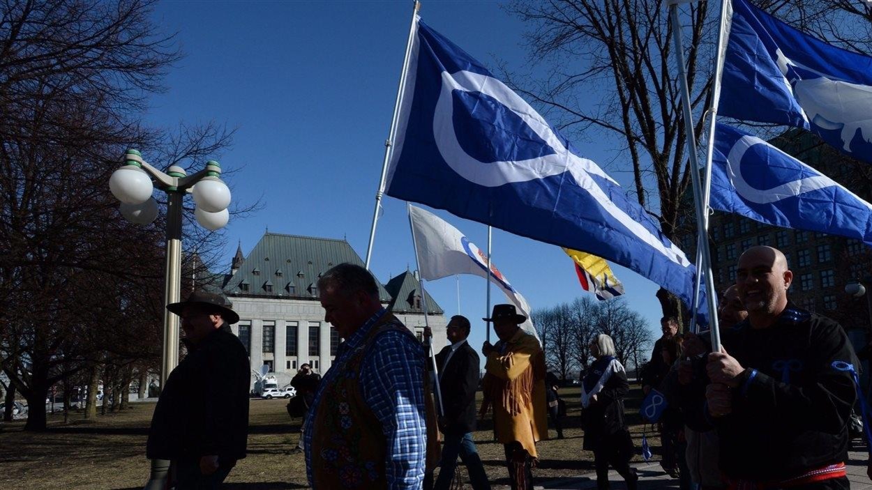 Des Métis défilent en tenant leur drapeau devant l'édifice abritant la Cour suprême du Canada, à Ottawa. Des Métis défilent en tenant leur drapeau devant l'édifice abritant la Cour suprême du Canada, à Ottawa.
