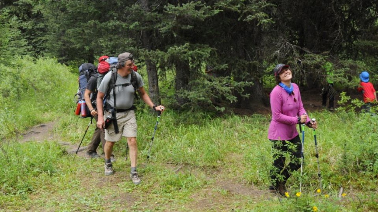 Une jeune femme habillé en rose marche dans les bois. Elle est accompagnée par d'autres participants. Une jeune femme habillé en rose marche dans les bois. Elle est accompagnée par d'autres participants.