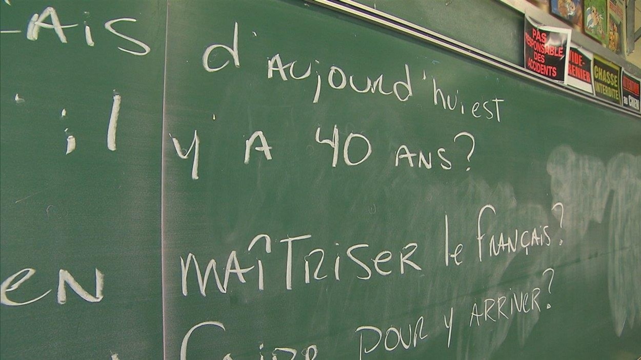Des phrases écrites en français sur un tableau dans une école.