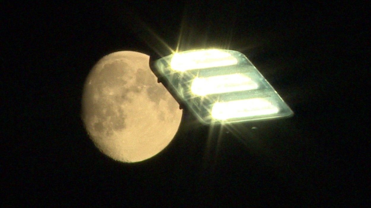 La pleine lune passe derrière un lampadère DEL. La pleine lune passe derrière un lampadère DEL.