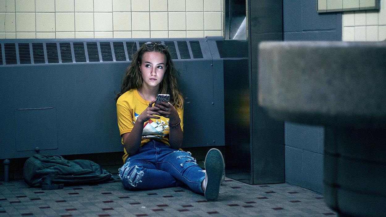 Une adolescente assise par terre consulte lad téléphone. Une adolescente assise par terre consulte lad téléphone.