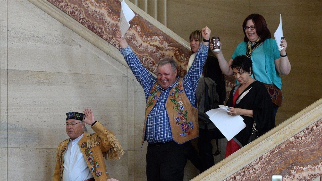 Des Métis descendent les marches de la Cour suprême en célébrant les bras dans les airs. Des Métis descendent les marches de la Cour suprême en célébrant les bras dans les airs.