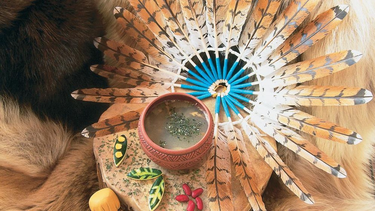 Récipient en terre avec le potage, une coiffe de plume traditionnelle wendate et fourrure. Récipient en terre avec le potage, une coiffe de plume traditionnelle wendate et fourrure.