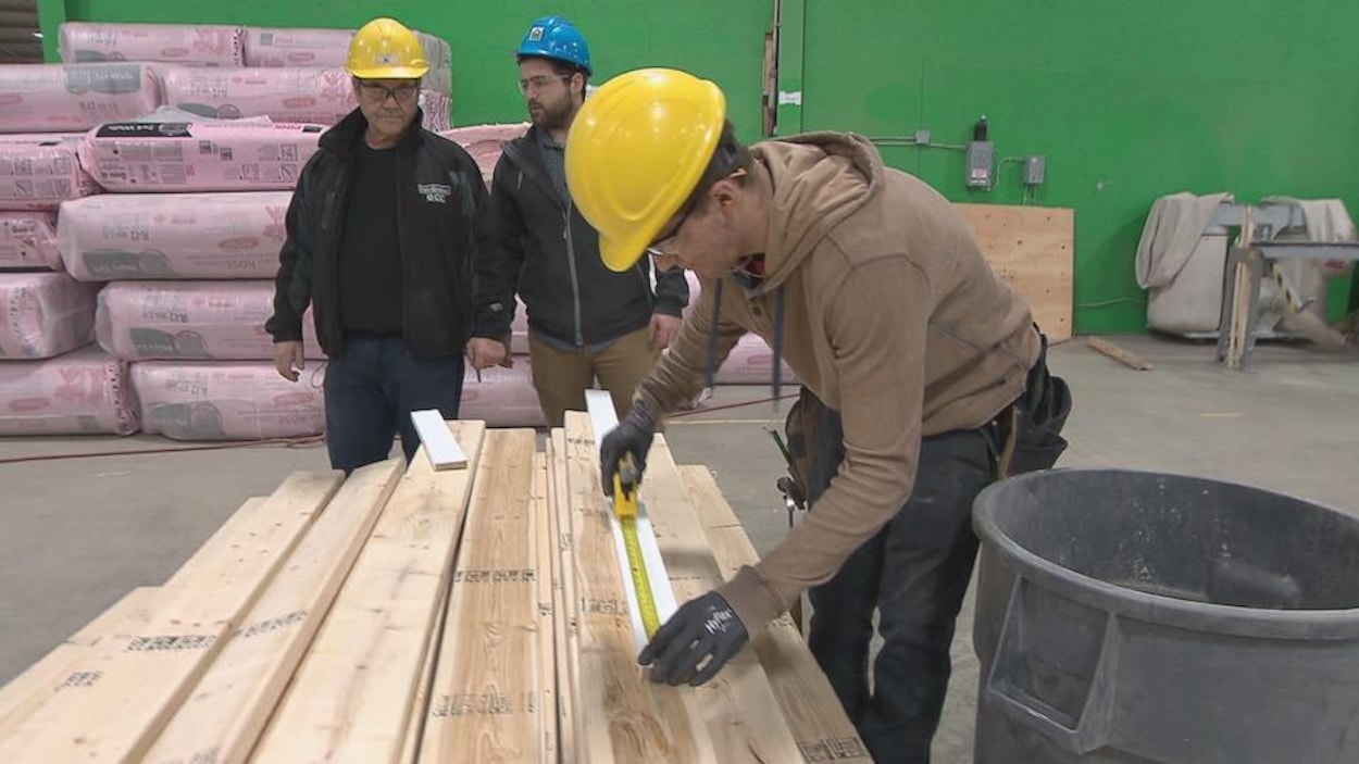 Un jeune stagiaire mesure une planche de bois. Un jeune stagiaire mesure une planche de bois.