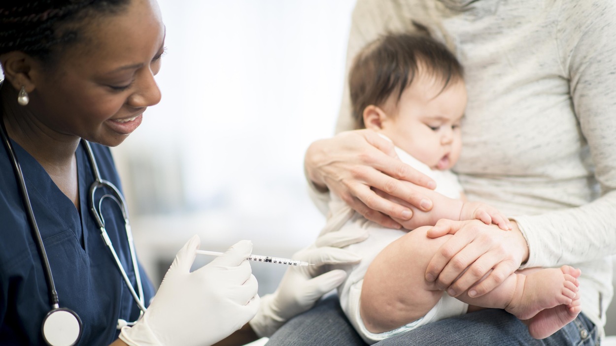 Un jeune enfant dans les bras de sa mère est sur le point de recevoir un vaccin. Un jeune enfant dans les bras de sa mère est sur le point de recevoir un vaccin.