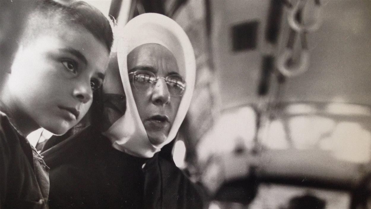 Une religieuse accompagnant un jeune garçon dans un autobus, à Montréal, été 1950. Une religieuse accompagnant un jeune garçon dans un autobus, à Montréal, été 1950.