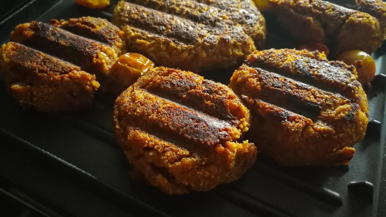 Des boulettes de burger cuisent sur un barbecue. Des boulettes de burger cuisent sur un barbecue.