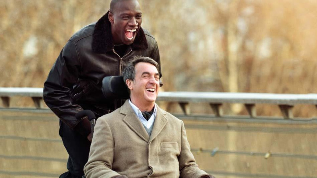 Un homme pousse un autre homme qui est en chaise roulante. Les deux rient. Un homme pousse un autre homme qui est en chaise roulante. Les deux rient.