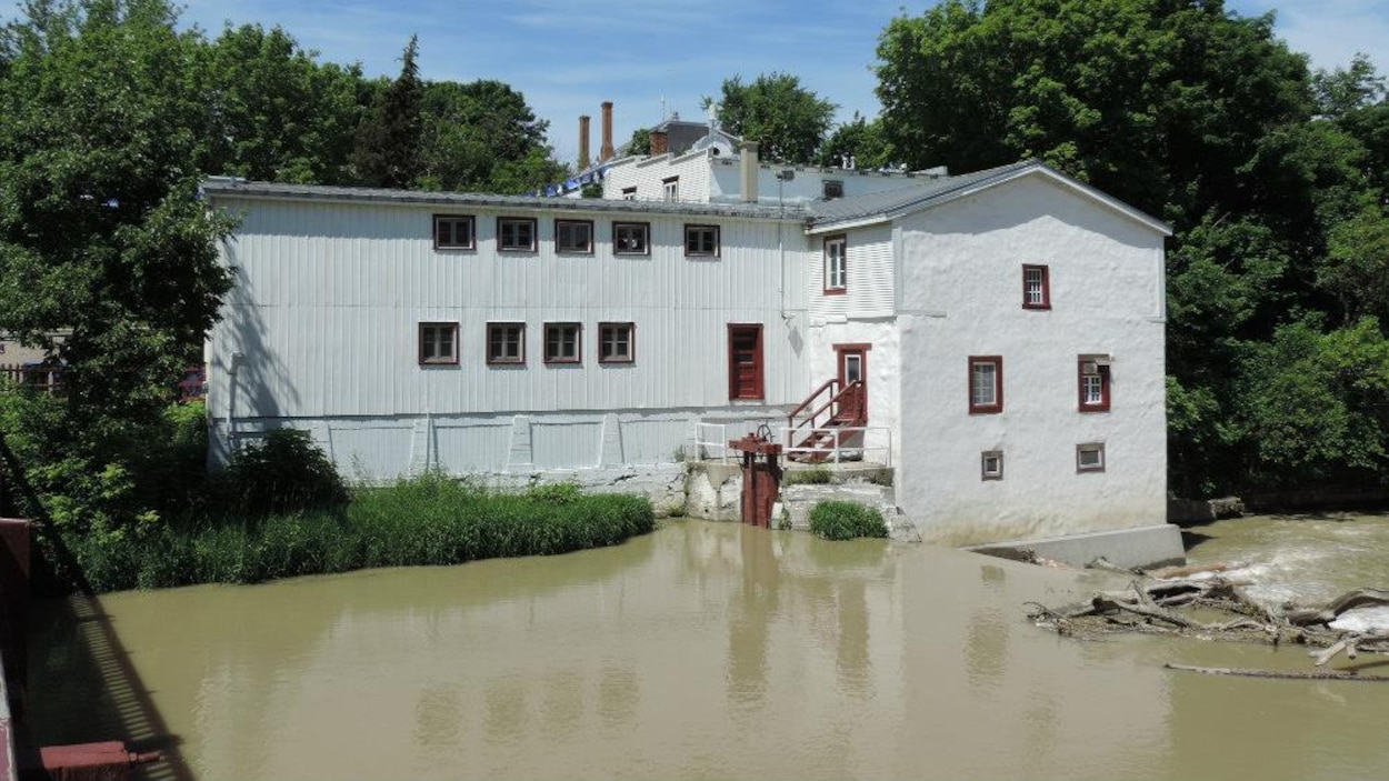 Un grand bâtiment blanc aux portes et fenêtres rouges près d'un cours d'eau. Un grand bâtiment blanc aux portes et fenêtres rouges près d'un cours d'eau.